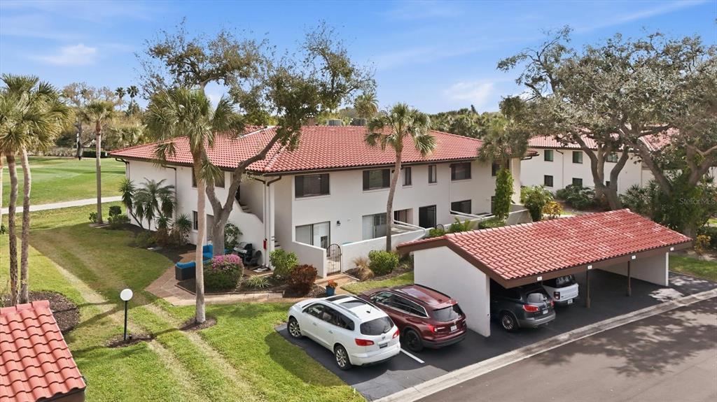 An exterior view of a two-story apartment building with a red tile roof and carport — 3500 EL CONQUISTADOR PARKWAY UNIT 144, BRADENTON, FL