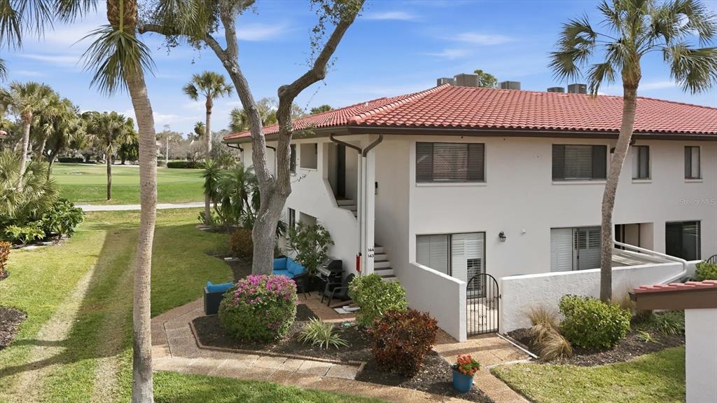 An exterior view of a two-story stucco building with a red tile roof — 3500 EL CONQUISTADOR PARKWAY UNIT 144, BRADENTON, FL