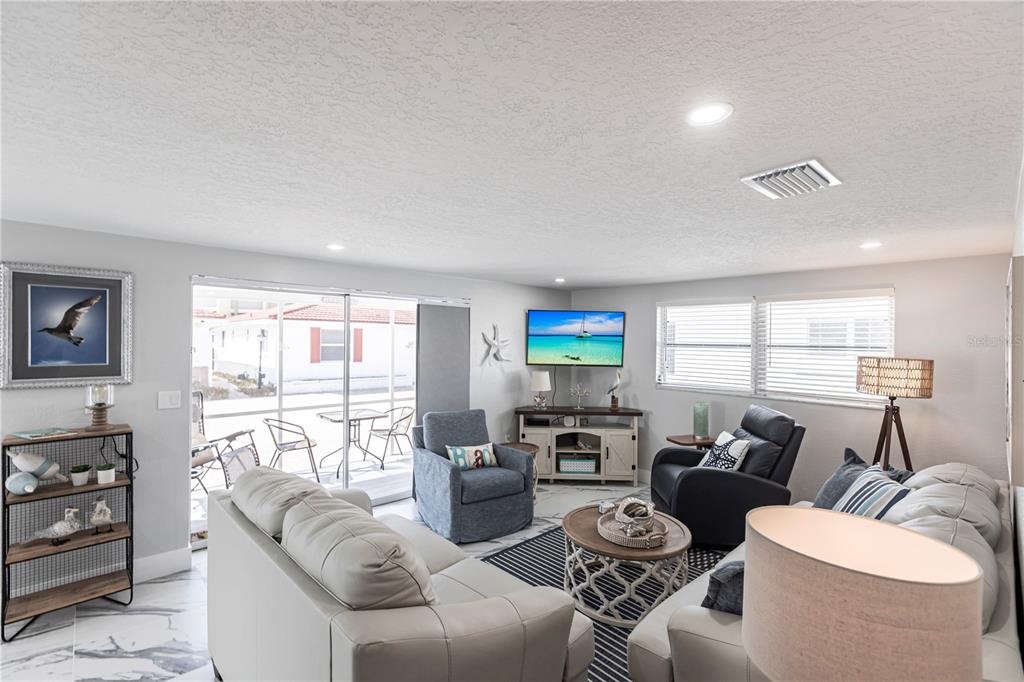 A living room features light-colored sofas, a blue armchair, a television, and tile flooring — 6154 MIDNIGHT PASS ROAD UNIT C16, SARASOTA, FL
