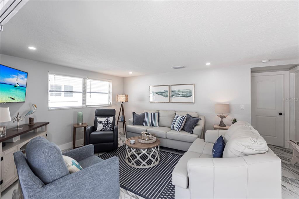 A living room features light-colored sofas, a blue armchair, a striped rug, and coastal decor — 6154 MIDNIGHT PASS ROAD UNIT C16, SARASOTA, FL
