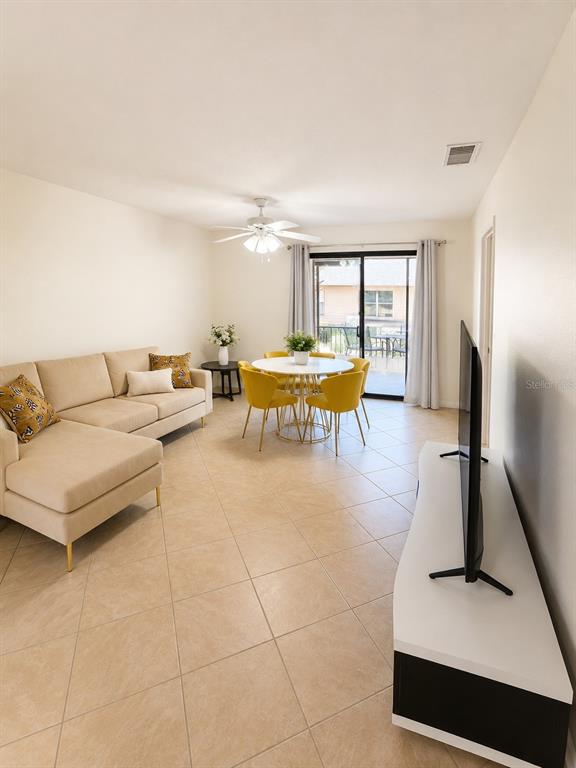 A living and dining area features beige tile floors, a sectional sofa, and yellow chairs — 5322 11TH STREET CIRCLE E UNIT 5322, BRADENTON, FL
