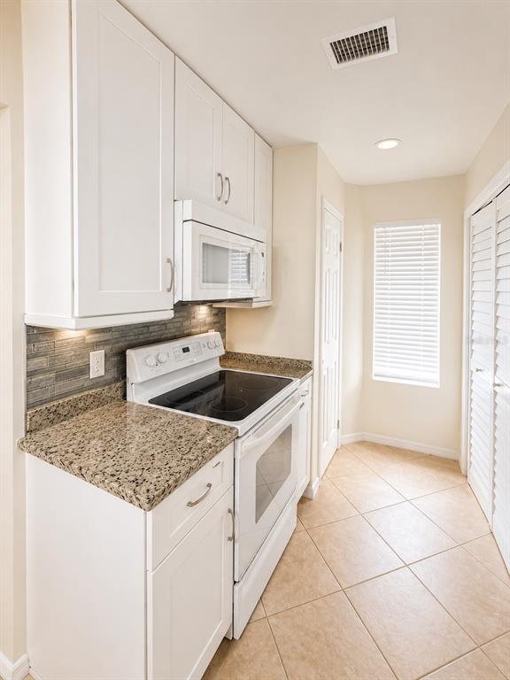 A kitchen features white cabinets, granite countertops, a glass-top stove, and light-colored tile flooring — 5322 11TH STREET CIRCLE E UNIT 5322, BRADENTON, FL