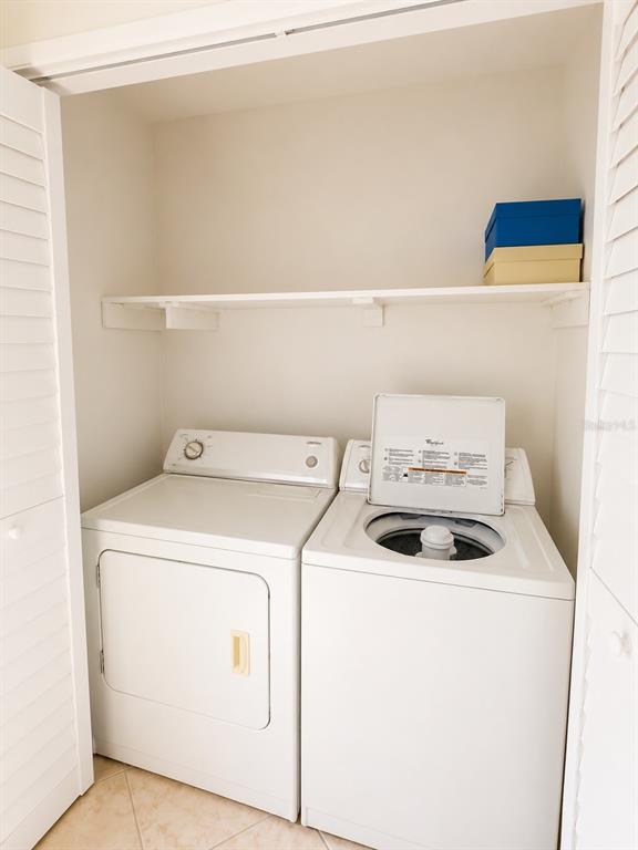 A white laundry closet contains a side-by-side washer and dryer with a storage shelf above — 5322 11TH STREET CIRCLE E UNIT 5322, BRADENTON, FL