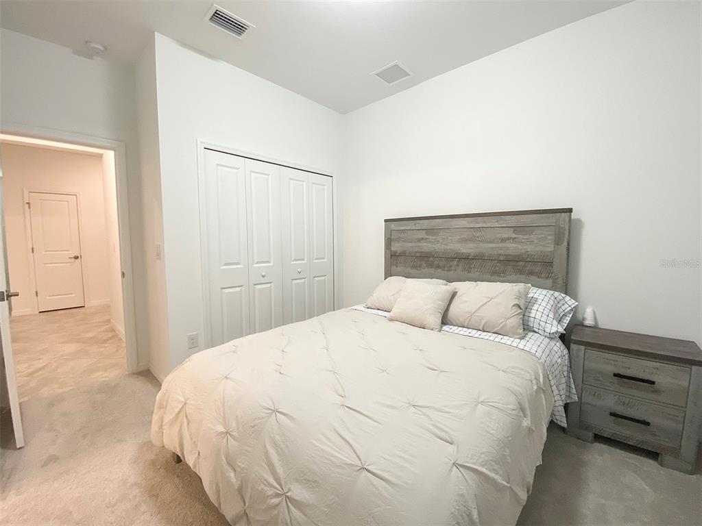 A bedroom features a bed with a wooden headboard, a nightstand, and a white closet — 15936 HONEYSUCKLE STREET, PORT CHARLOTTE, FL