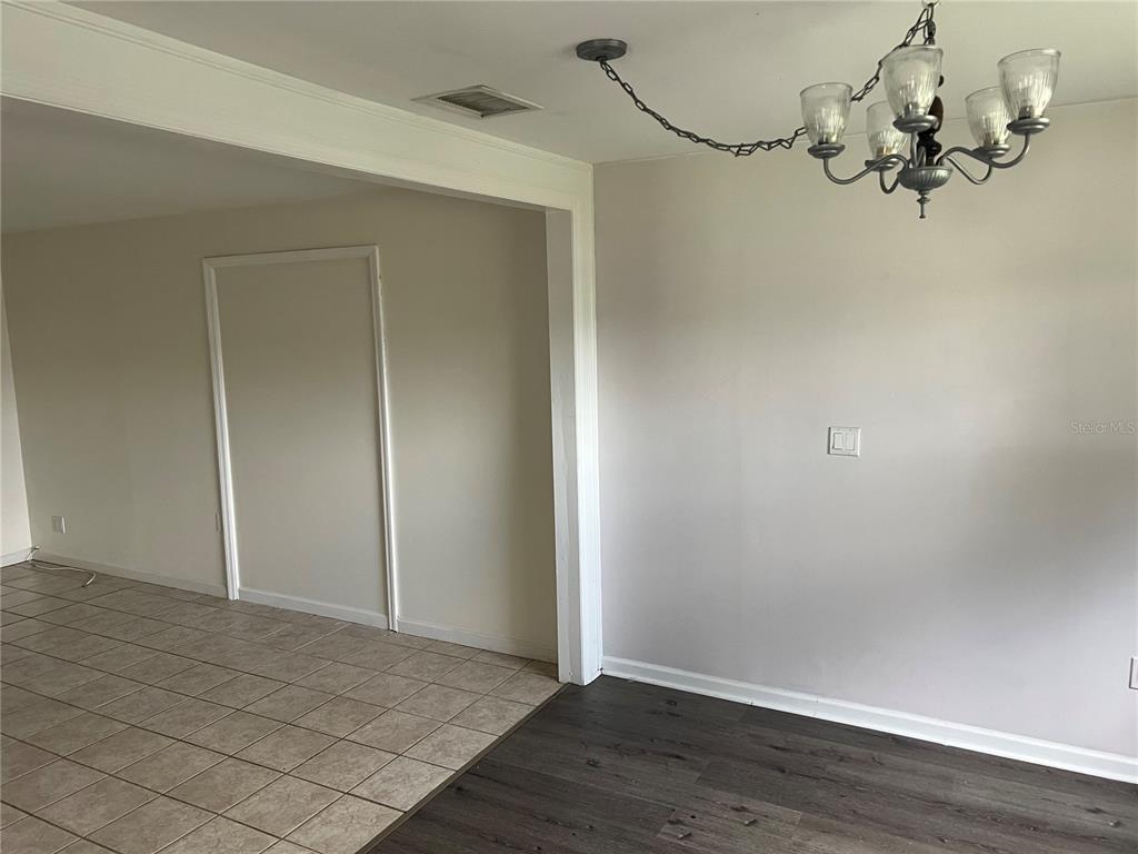 A kitchen with white cabinets, stainless steel appliances, and wood-look flooring leads to another room — 3101 W DEWEY STREET, TAMPA, FL