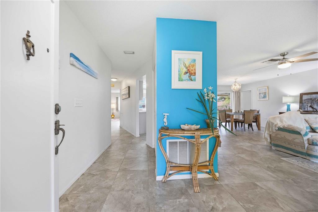 An entryway features a bright blue accent wall, a rattan console table, and tile flooring — 119 VAN DYCK DRIVE, NOKOMIS, FL