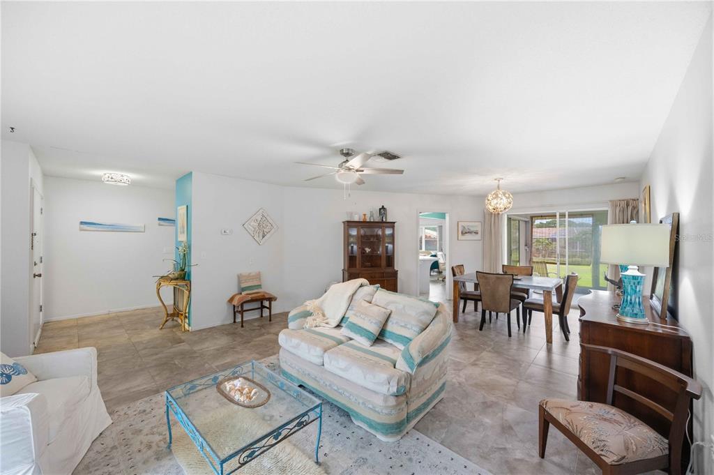 A living and dining area with tile floors, a ceiling fan, and sliding glass doors — 119 VAN DYCK DRIVE, NOKOMIS, FL