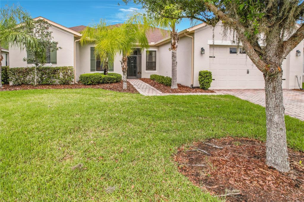 A single-story house with a beige exterior, a two-car garage, and a landscaped front yard — 477 VILLA PARK ROAD, POINCIANA, FL