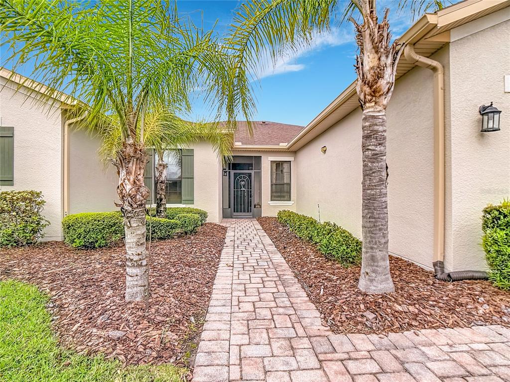 A paved walkway leads to the front entrance of a house with palm trees — 477 VILLA PARK ROAD, POINCIANA, FL