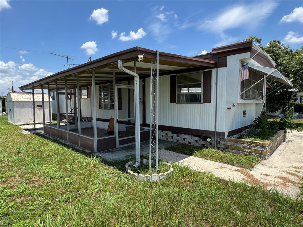 A single-story mobile home with a screened-in porch, metal siding, and a small storage shed — 37309 8TH AVENUE UNIT 161, ZEPHYRHILLS, FL
