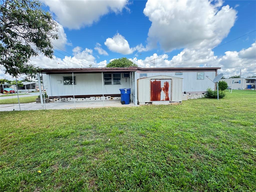 The exterior of a mobile home features a covered patio, a shed, and a lawn — 37309 8TH AVENUE UNIT 161, ZEPHYRHILLS, FL