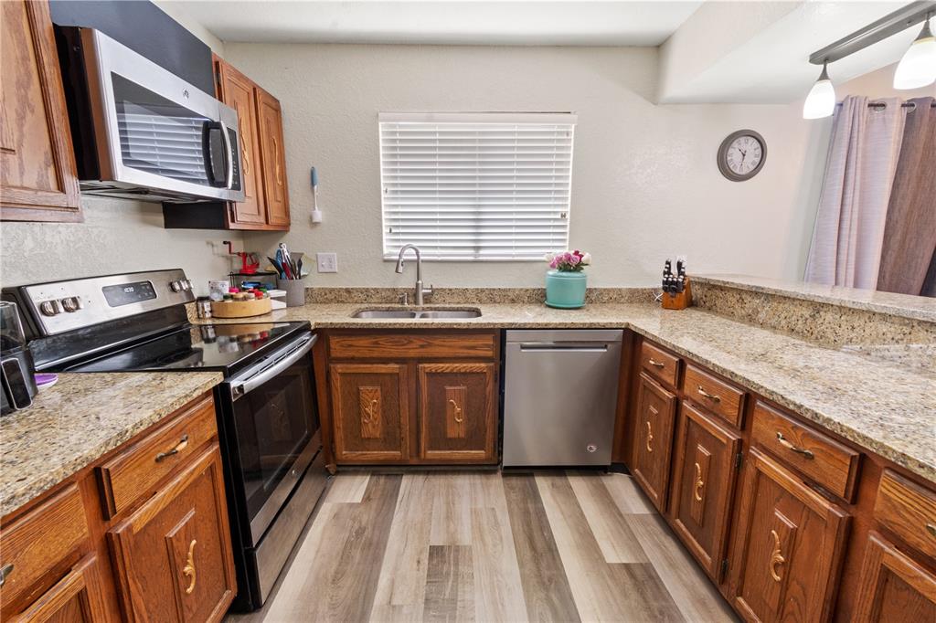 A kitchen features wood cabinets, granite countertops, stainless steel appliances, and wood-look flooring — 1836 N CRYSTAL LAKE DRIVE UNIT 27, LAKELAND, FL