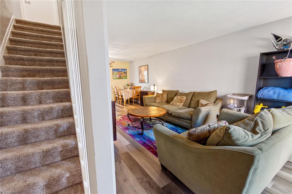 A carpeted staircase leads down to a living room with wood-look flooring and a rug — 1836 N CRYSTAL LAKE DRIVE UNIT 27, LAKELAND, FL