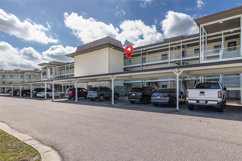 A multi-story apartment building features covered parking spaces in front of the structure — 4660 MARINE PARKWAY UNIT 303, NEW PORT RICHEY, FL