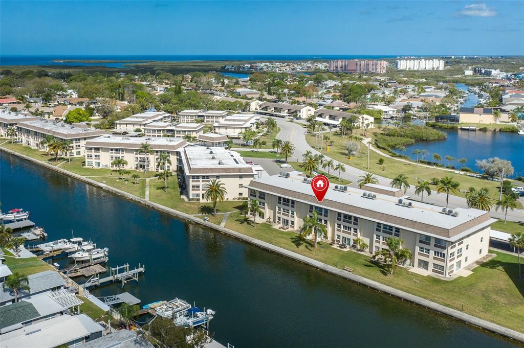 An aerial view shows multi-story apartment buildings situated along a canal with boat docks — 4660 MARINE PARKWAY UNIT 303, NEW PORT RICHEY, FL