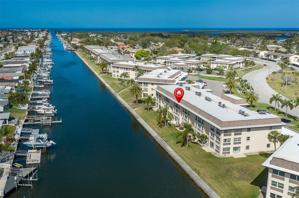 An aerial view shows a waterfront apartment building with a canal and docked boats — 4660 MARINE PARKWAY UNIT 303, NEW PORT RICHEY, FL