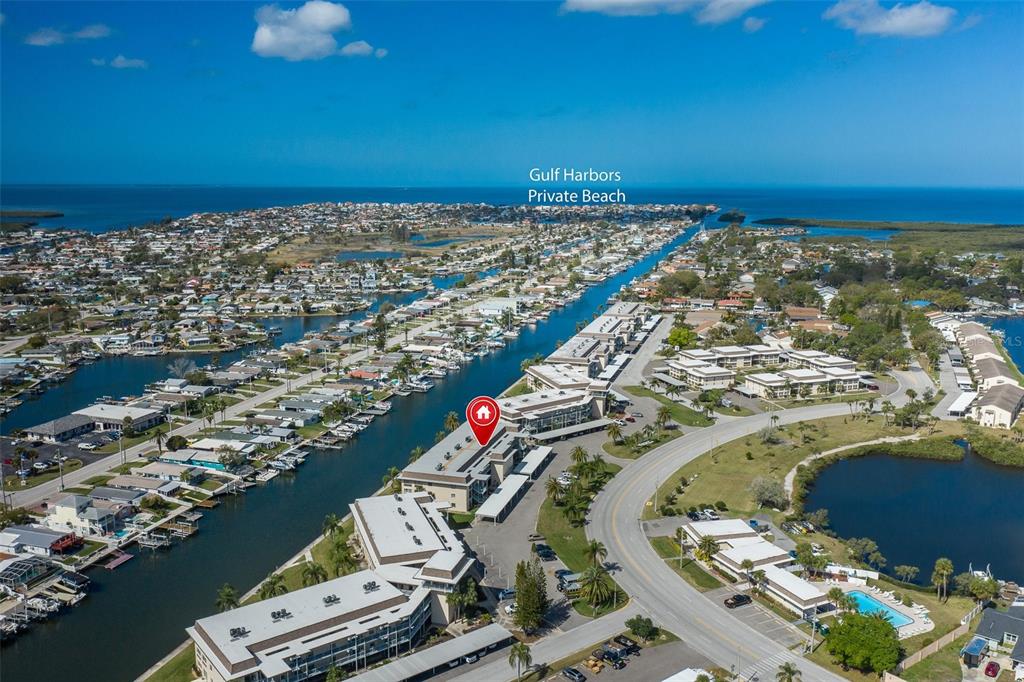 An aerial view shows a multi-story apartment complex situated along a canal near the coast — 4660 MARINE PARKWAY UNIT 303, NEW PORT RICHEY, FL