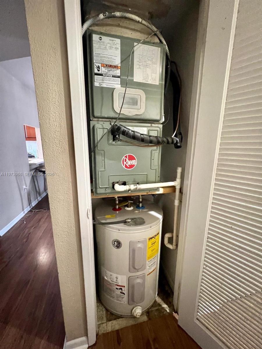 A closet contains a Rheem air handler unit stacked above a GE water heater — 1700 NE 191st St # 508, Miami FL 33179, MIAMI, FL