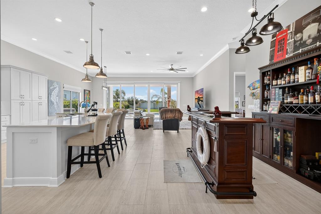A spacious open-concept kitchen and bar area with light tile floors and large sliding doors — 94 DEL PALMA DRIVE, PALM COAST, FL