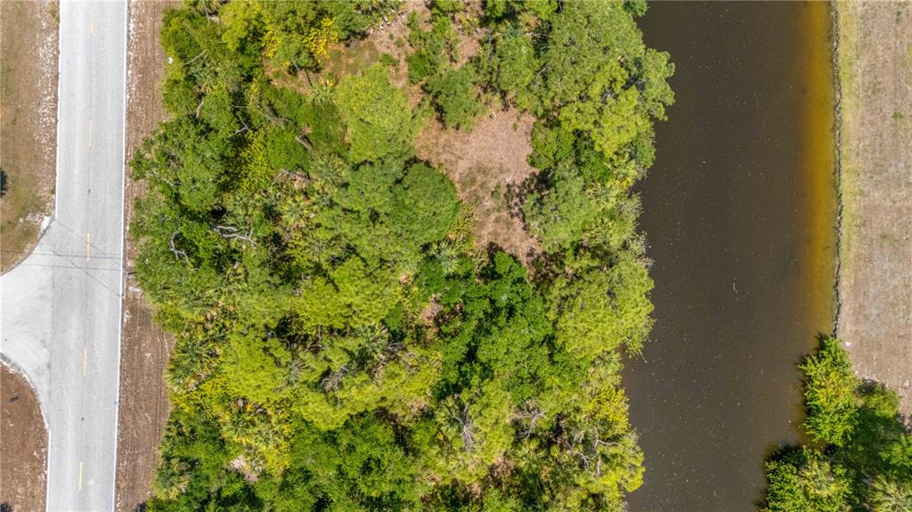 An aerial view shows a wooded lot situated between a paved road and a canal — 2042 COMO STREET, PORT CHARLOTTE, FL