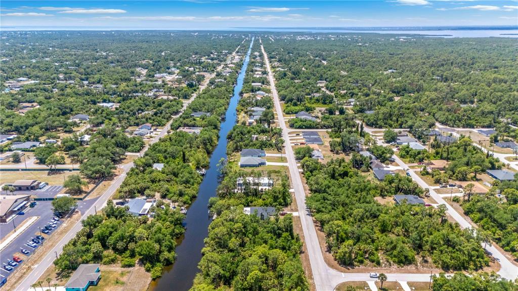 An aerial view shows a canal running between two roads lined with houses and trees — 2042 COMO STREET, PORT CHARLOTTE, FL