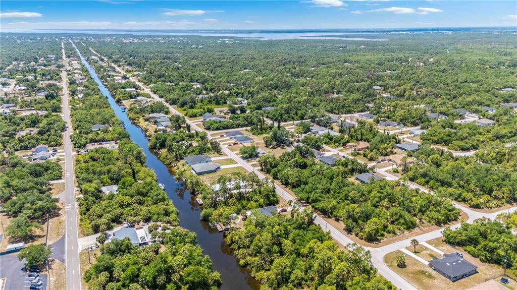 An aerial view shows a canal running through a residential neighborhood surrounded by dense trees — 2042 COMO STREET, PORT CHARLOTTE, FL