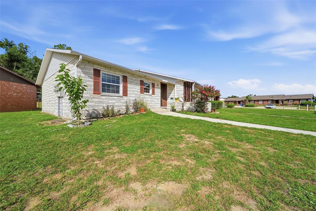 A single-story house with white stone siding and brown shutters sits on a grassy lawn — 10310 BLUE FIELD CT, THONOTOSASSA, FL