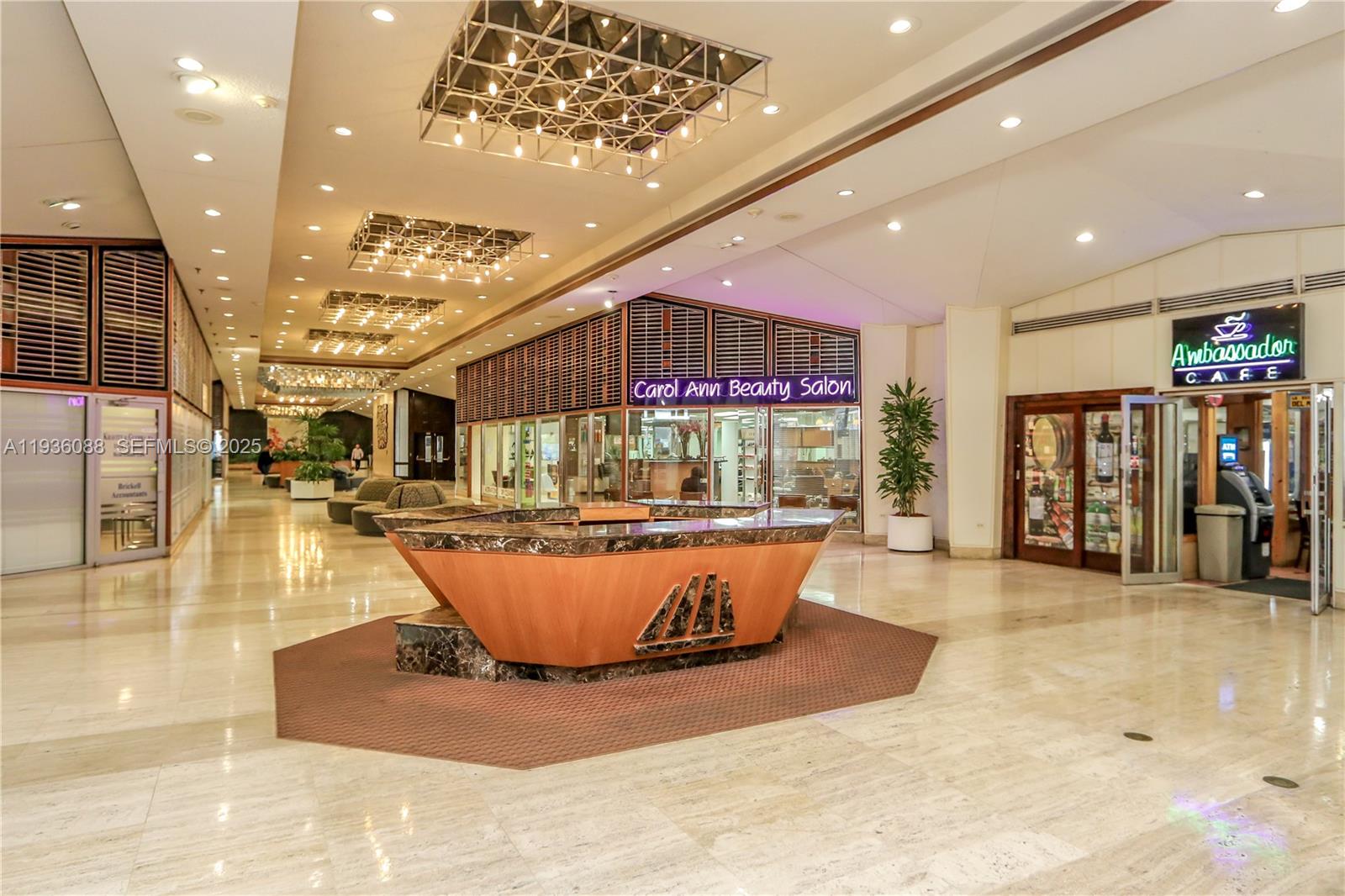 A lobby features a central marble reception desk, recessed lighting, and storefronts for a salon and cafe — 825 Brickell Bay Dr, Miami FL 33131, MIAMI, FL