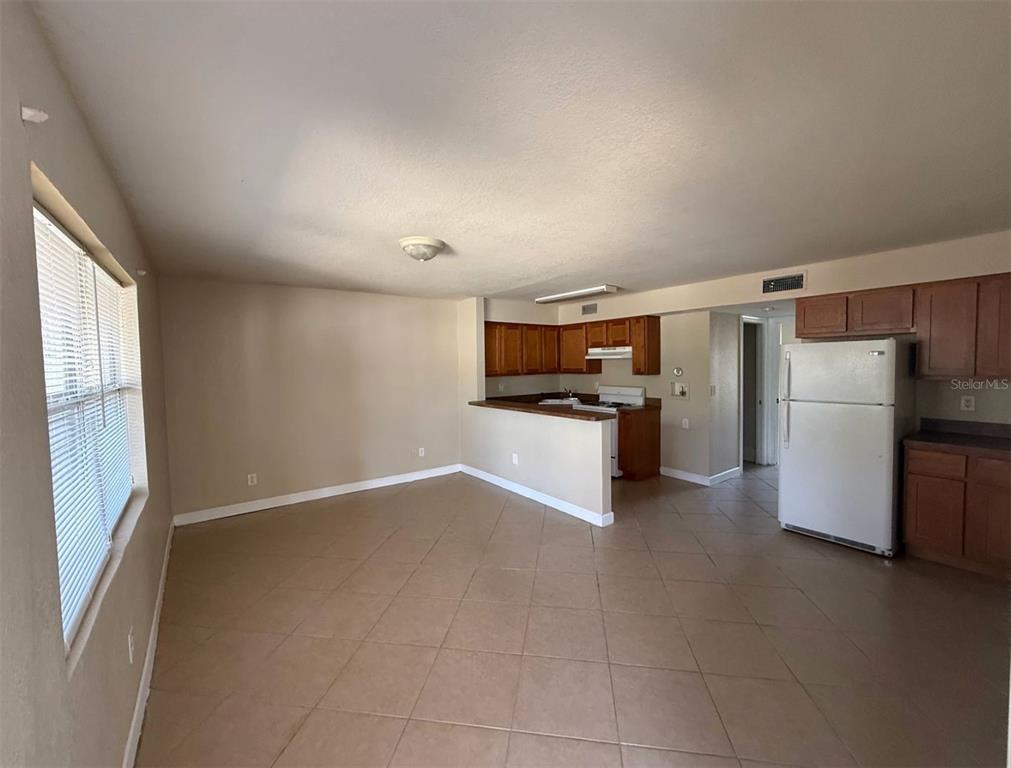 An open-concept kitchen and living area with tile flooring and wood cabinetry — 117 N EVERGREEN AVENUE UNIT 102, CLEARWATER, FL