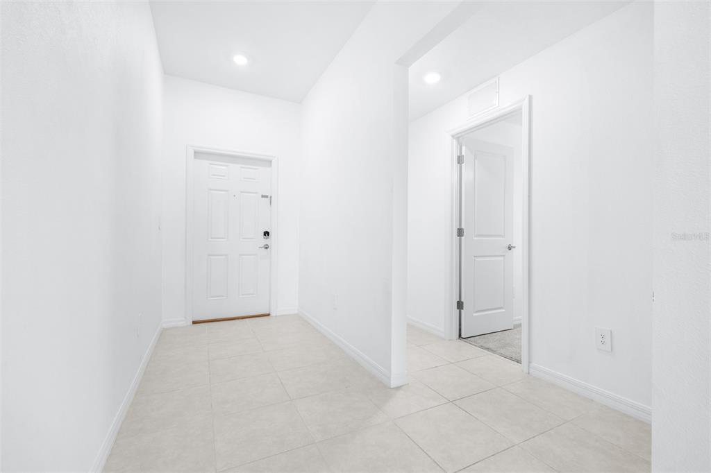 A bright entryway features white walls, tiled flooring, a front door, and an interior door — 4312 FABULOUS FINCH LANE, BARTOW, FL