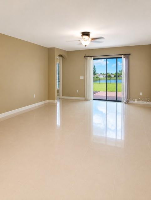 A living room with beige walls, tile flooring, a ceiling fan, and sliding glass doors — 171 SHADOWVIEW COURT, LEHIGH ACRES, FL
