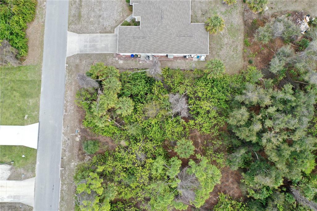 An aerial view shows a house with a driveway next to a wooded lot — KENVIL DRIVE, NORTH PORT, FL