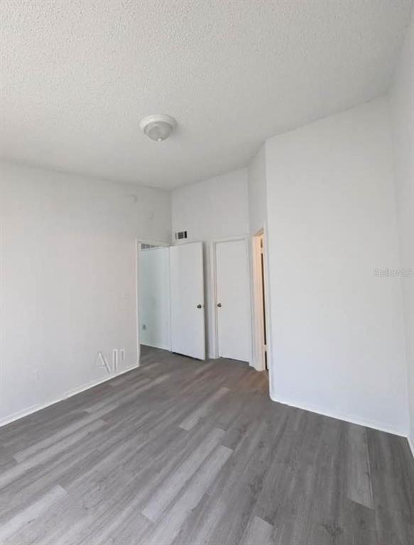 An empty room features white walls, a ceiling light, and gray wood-look flooring — 1956 LAKE ATRIUMS CIRCLE UNIT 144, ORLANDO, FL