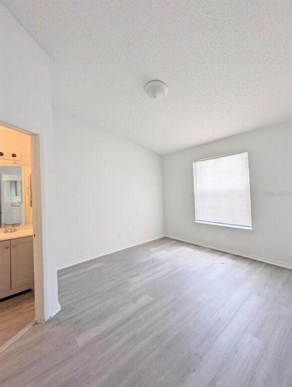 An empty bedroom with light-colored wood-look flooring, white walls, and a window with blinds — 1956 LAKE ATRIUMS CIRCLE UNIT 144, ORLANDO, FL