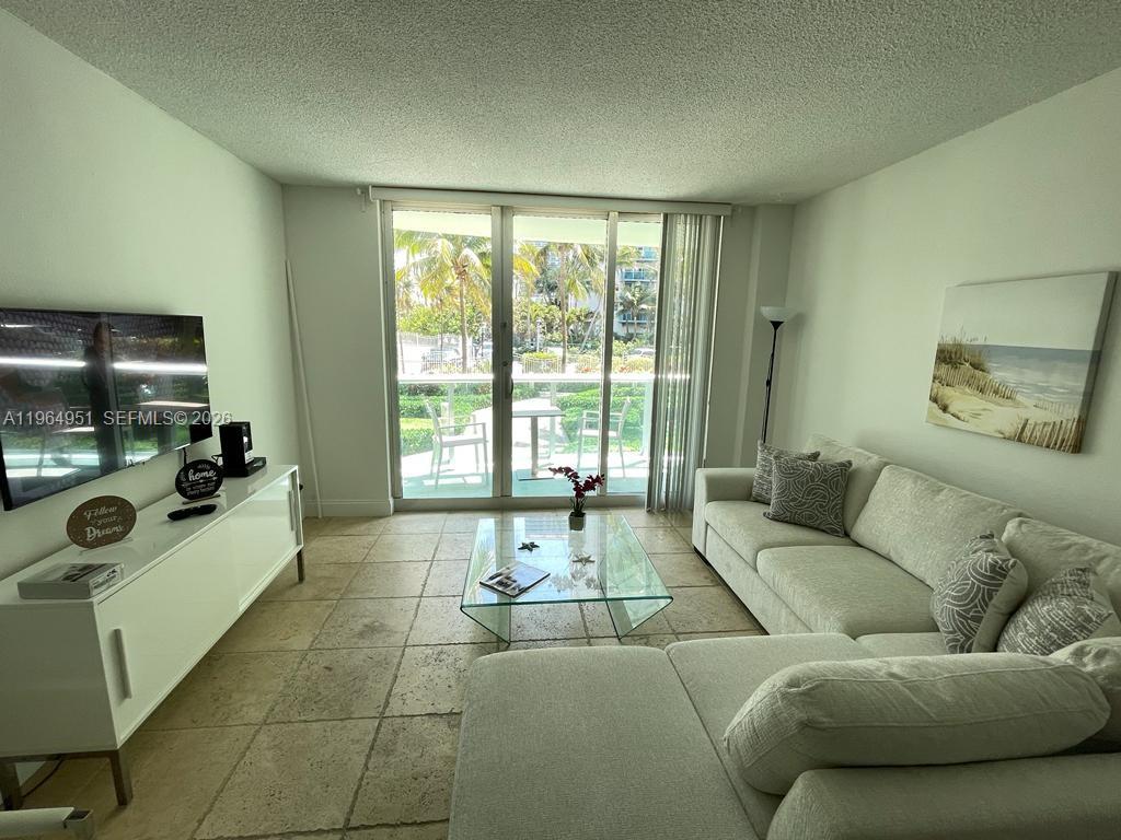 A living room features a white sectional sofa, a glass coffee table, and tile flooring — 3901 S Ocean Dr # 1J, Hollywood FL 33019, HOLLYWOOD, FL