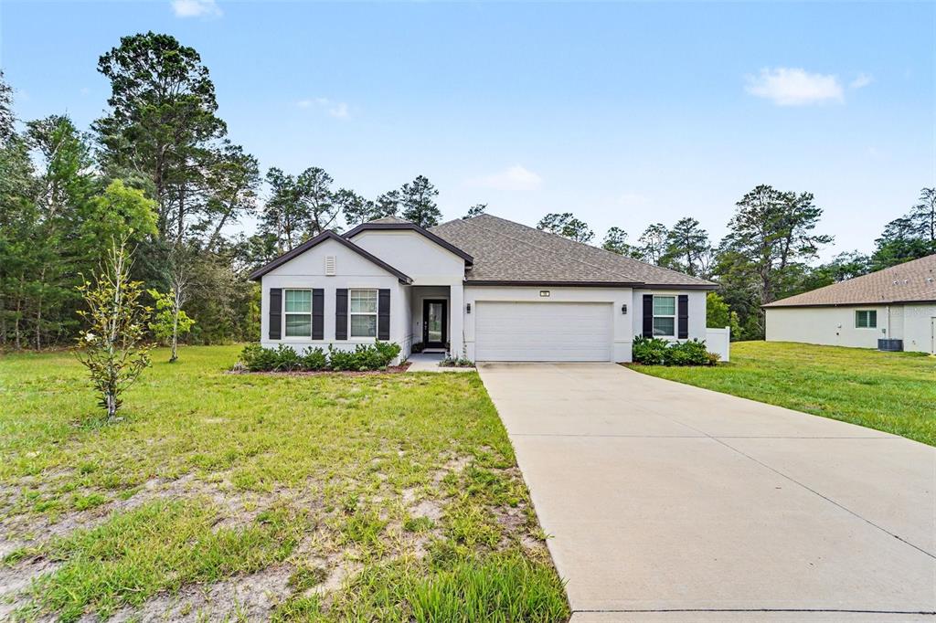 A single-story house with a white exterior, a two-car garage, and a concrete driveway — 15 LONE PINE STREET, HOMOSASSA, FL