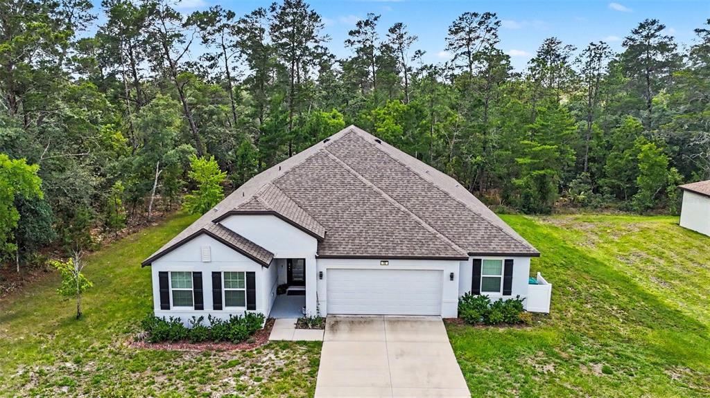 An aerial view of a single-story house with a white exterior, garage, and shingled roof — 15 LONE PINE STREET, HOMOSASSA, FL