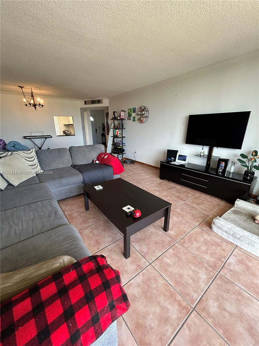 A living room features a gray sectional sofa, a dark coffee table, and a television console — 1501 NE 191st St # C401, Miami FL 33179, MIAMI, FL