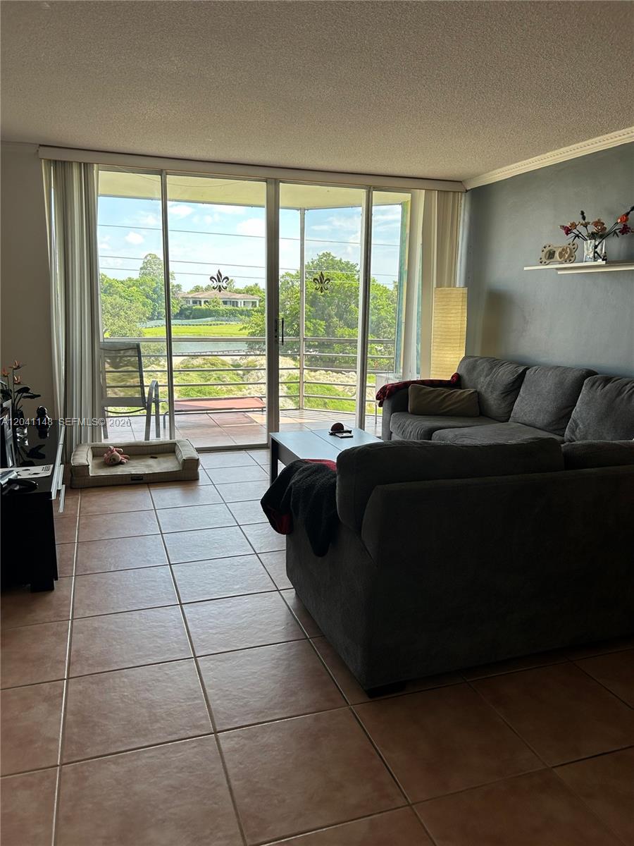A living room features tile flooring, a gray sectional sofa, and sliding glass doors — 1501 NE 191st St # C401, Miami FL 33179, MIAMI, FL
