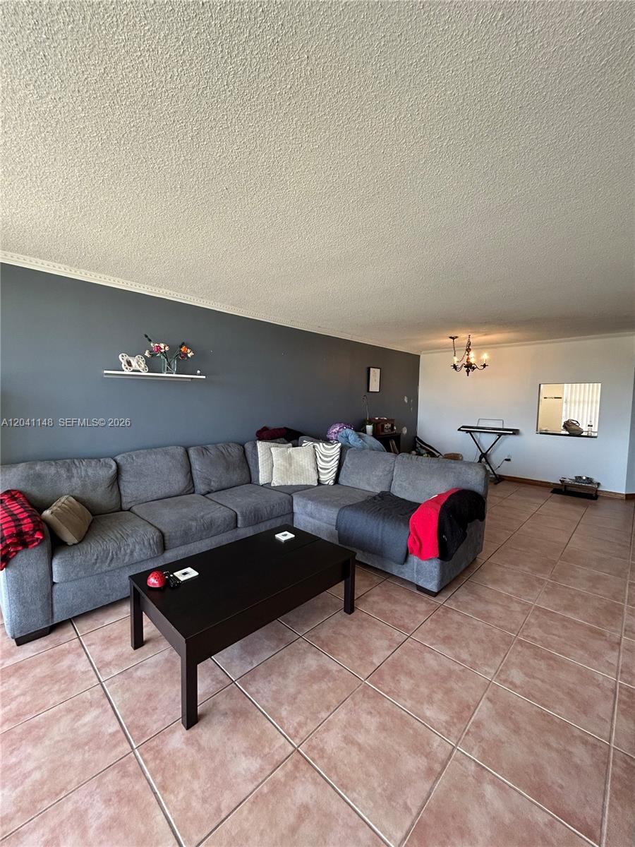 A living room features a grey sectional sofa, a black coffee table, and tiled flooring — 1501 NE 191st St # C401, Miami FL 33179, MIAMI, FL