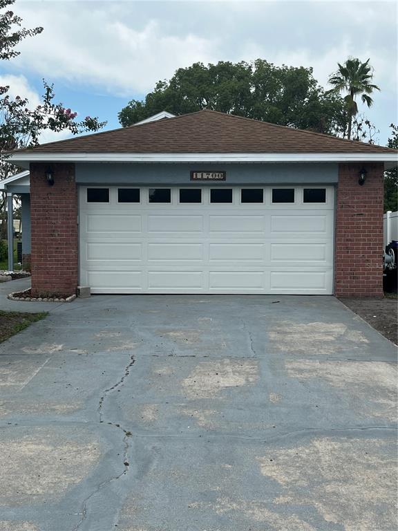 A covered front porch features a white door, brick accents, and a gray painted floor — 11700 MINTO COURT, ORLANDO, FL