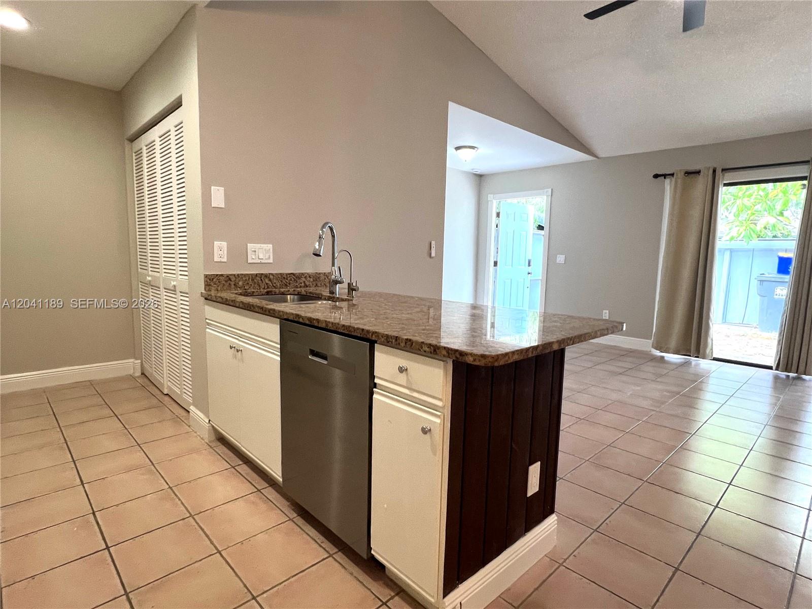 A kitchen island with a stainless steel dishwasher and sink sits on a tiled floor — 1077 Goldenrod Rd # 1077, Wellington FL 33414, WELLINGTON, FL
