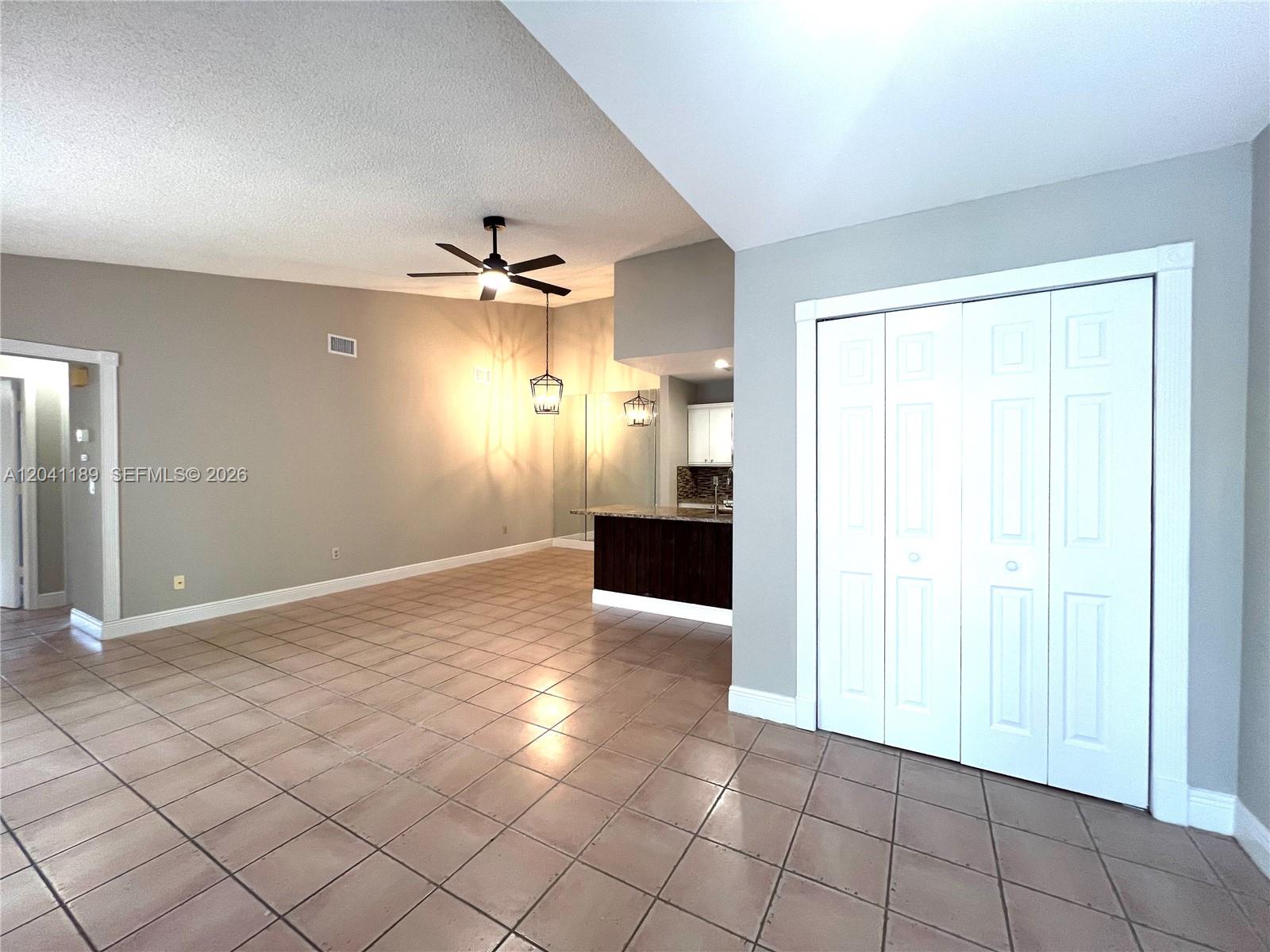 An open-concept living area features tile flooring, a ceiling fan, and a kitchen island — 1077 Goldenrod Rd # 1077, Wellington FL 33414, WELLINGTON, FL