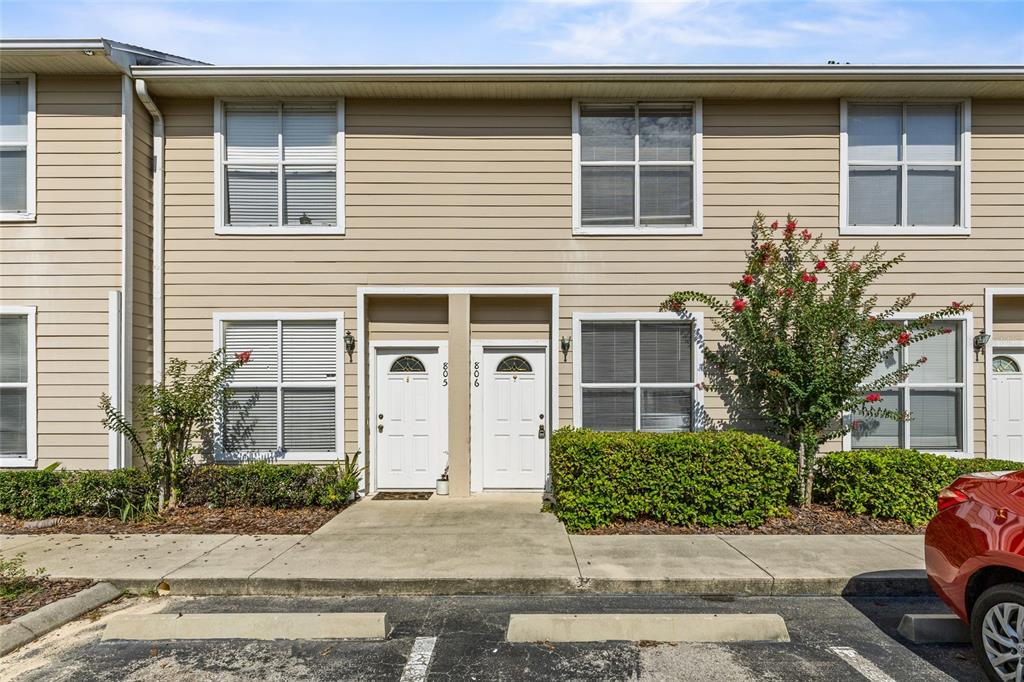 The exterior of a two-story tan townhouse features two white front doors and parking spaces — 3901 SW 20TH AVENUE UNIT 806, GAINESVILLE, FL