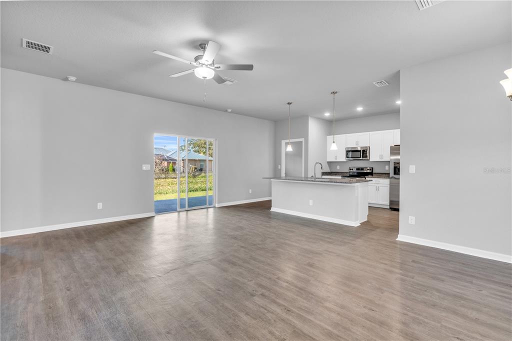 An open-concept living area with wood-look flooring, a ceiling fan, and a kitchen with island — 5289 GILLOT BOULEVARD, PORT CHARLOTTE, FL