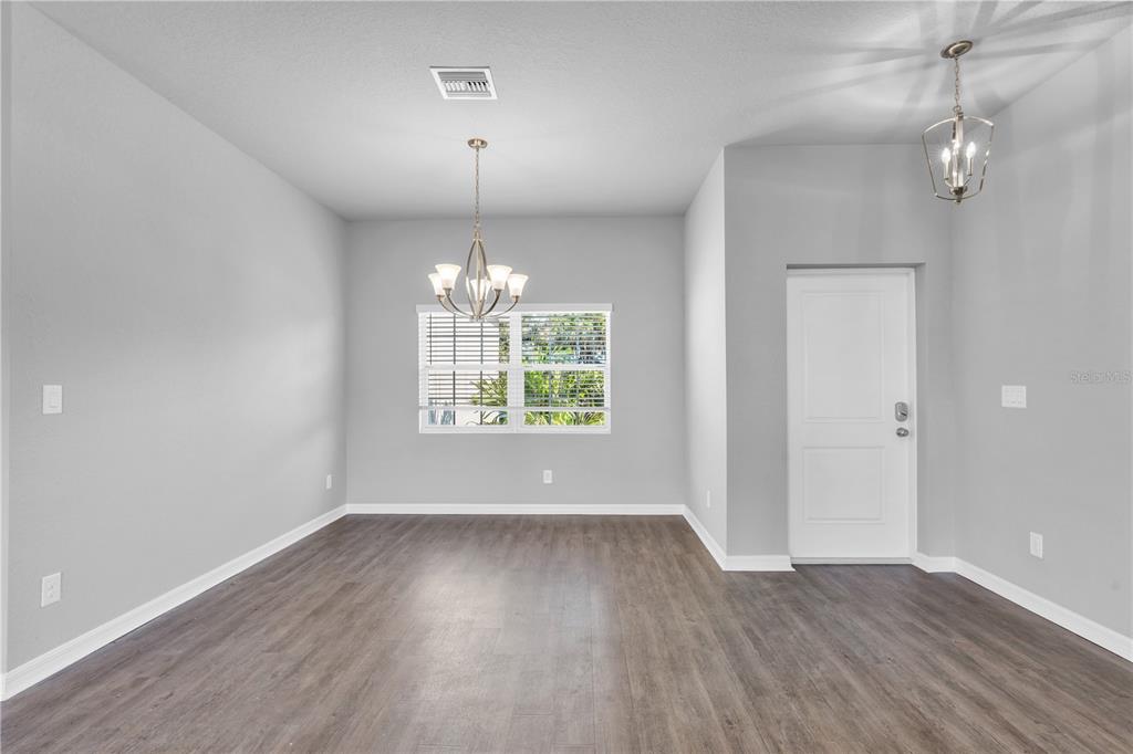 A dining room with light gray walls, dark wood-look flooring, and two hanging light fixtures — 5289 GILLOT BOULEVARD, PORT CHARLOTTE, FL