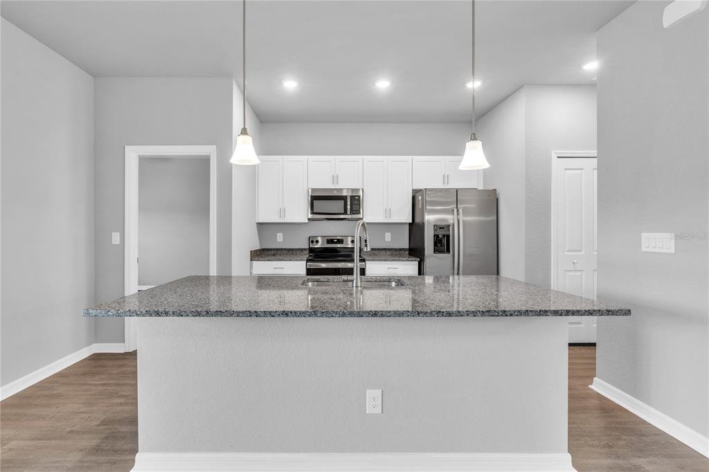 A kitchen features white cabinets, granite countertops, stainless steel appliances, and a central island — 5289 GILLOT BOULEVARD, PORT CHARLOTTE, FL