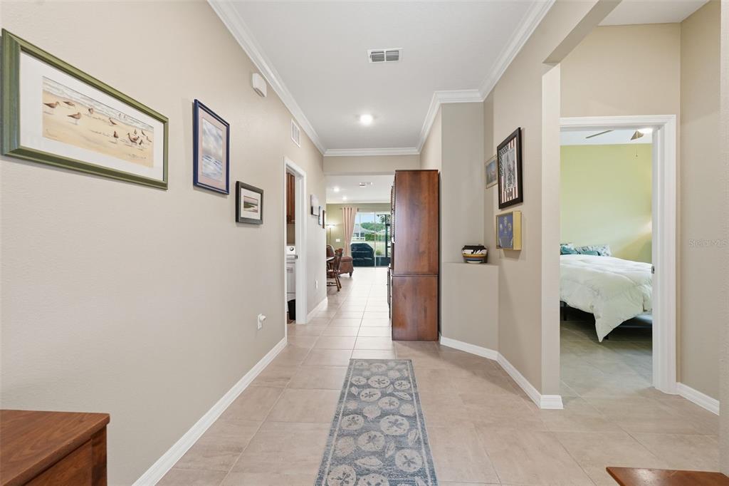 A tiled hallway leads past a bedroom and kitchen toward a living area with patio doors — 9958 SW 97TH LANE, OCALA, FL