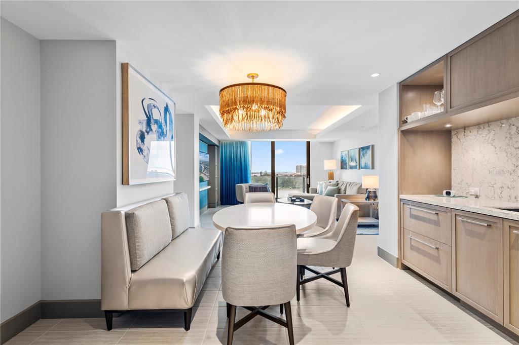 A dining area features a round table, upholstered chairs, a bench, and a gold chandelier — 691 S GULFVIEW BOULEVARD UNIT 1211, CLEARWATER BEACH, FL