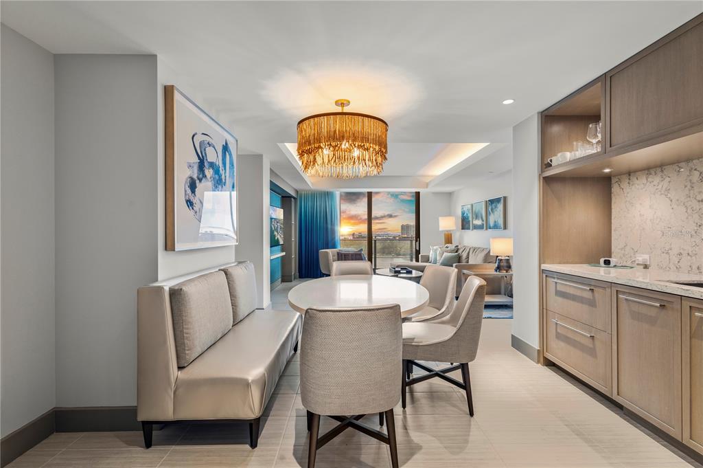 A dining area with a round table, upholstered chairs, a bench, and a gold chandelier — 691 S GULFVIEW BOULEVARD UNIT 1211, CLEARWATER BEACH, FL